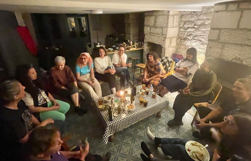 A fireside circle of womxn gathered in a living room on Portland